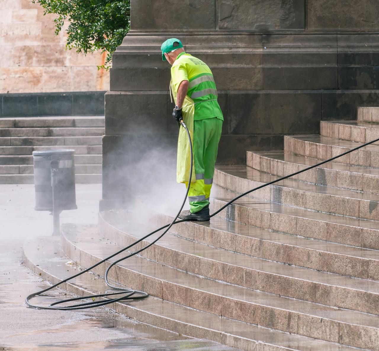 services-01 A street worker pressure washes stone stairs in a public park, ensuring cleanliness and safety.
