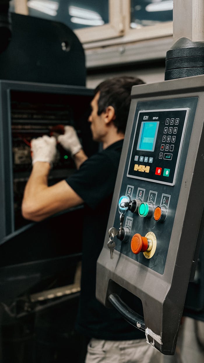 gallery-6 Technician using a control panel to manage machinery operations in a factory.