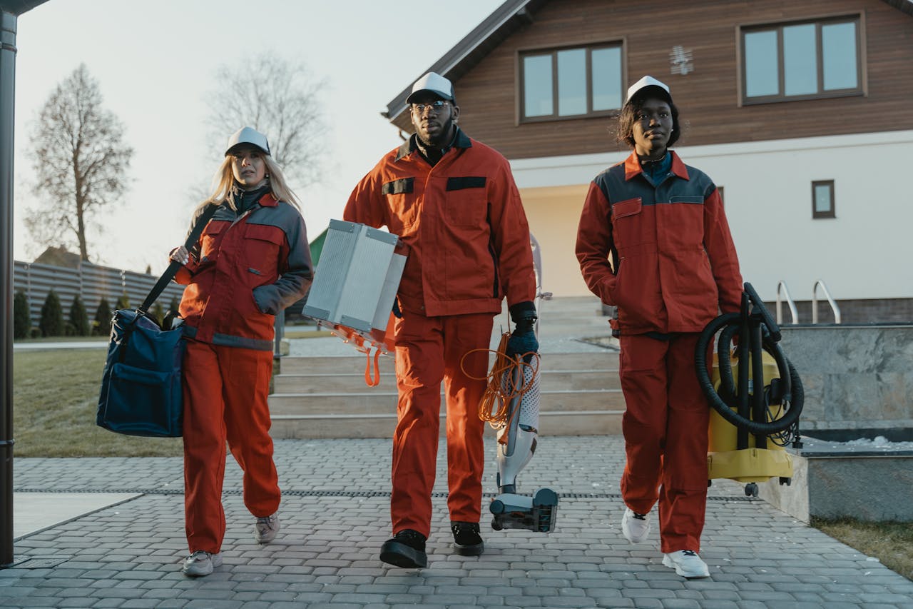 ours-journey A diverse team of professional cleaners walking outdoors in uniform, holding tools.